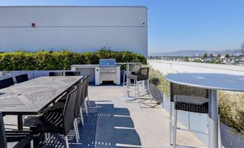 a rooftop patio with tables and chairs and a barbecue grill